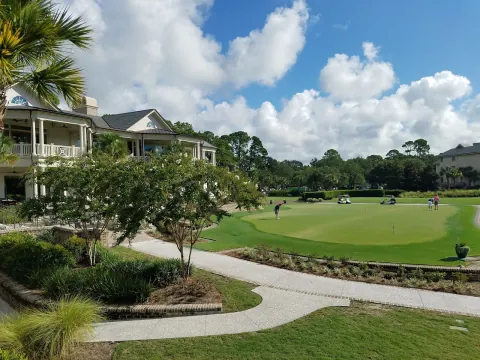 Golfers on the putting green beside the white, two-storey Harbour Town Clubhouse