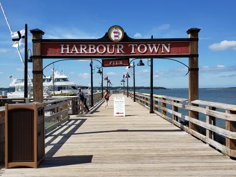 The Harbour Town pier entrance sign, with yachts in the marina and Calibogue Sound beyond