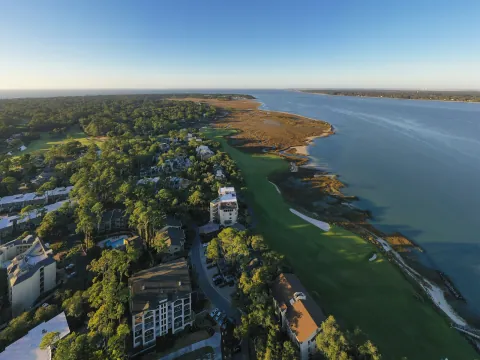 Aerial view of Sea Pines: villas among the pines beside a fairway that runs along the marsh of Calibogue Sound