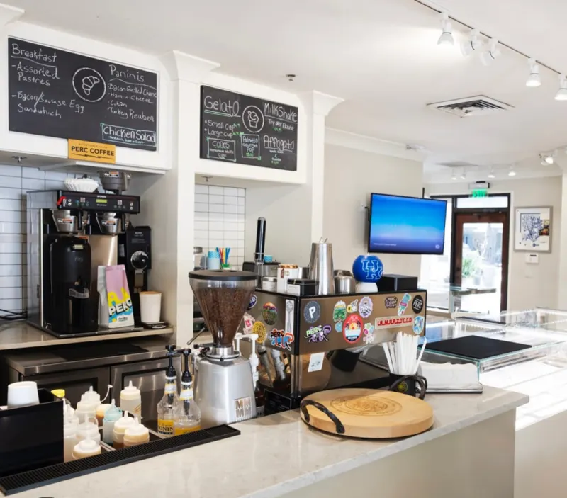 The coffee counter at C’est Bon, with an espresso machine and chalkboard menus for breakfast, paninis and gelato