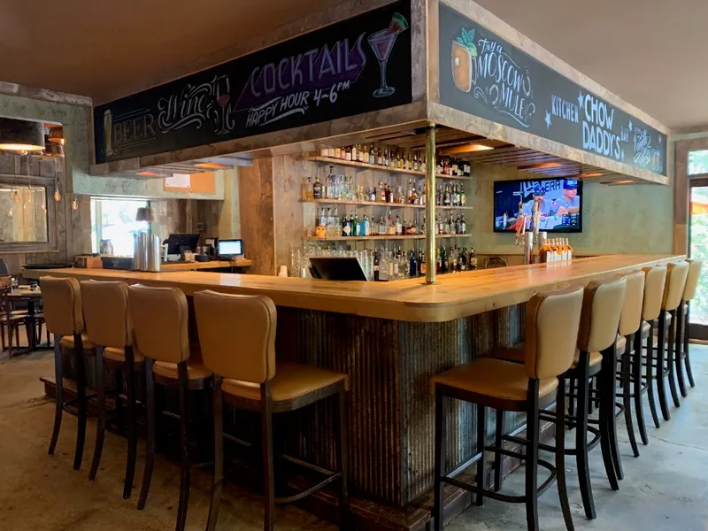 The long wood bar at Chow Daddy's with a chalkboard menu and the restaurant's name above the bar