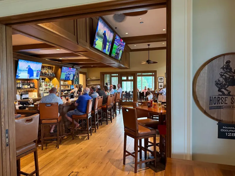 The bar at Fraser’s Tavern in Sea Pines, with leather bar stools, wood paneling and golf on the TVs