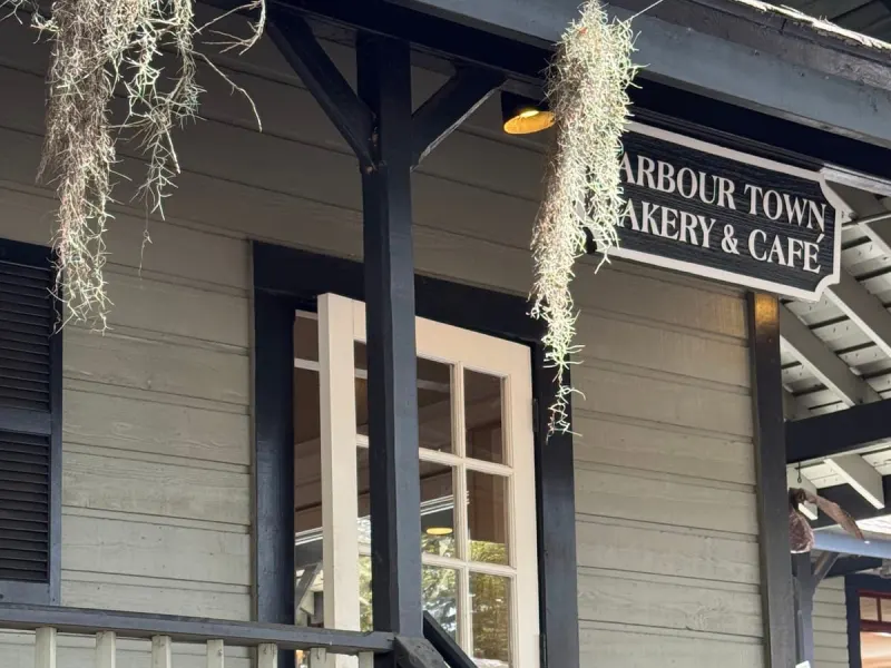 The porch and sign of Harbour Town Bakery and Café, a gray clapboard building hung with Spanish moss
