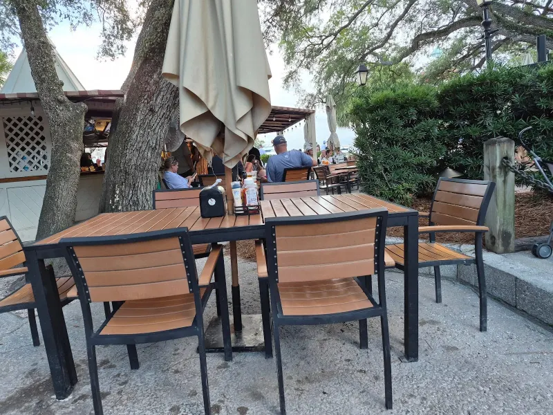 Outdoor tables under the live oaks at Harbourside in Harbour Town, with the covered bar behind