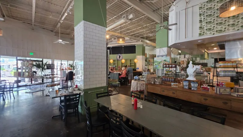 Inside Lowcountry Produce Market and Café at Sea Pines Center, long wooden tables beside shelves of jarred goods