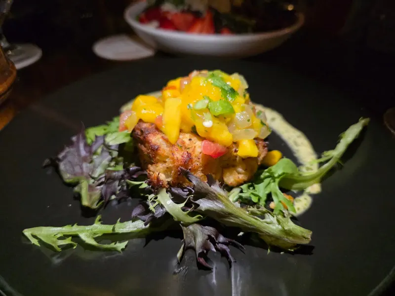 A crab cake topped with mango salsa on a bed of greens, served at the Ocean Lounge