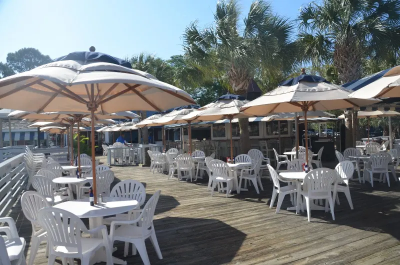 The Salty Dog Cafe deck at South Beach Marina, white tables under navy and cream umbrellas and palm trees