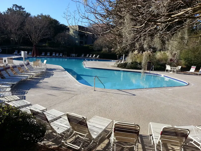 Harbour Town Pool in Sea Pines, a freeform pool ringed with white lounge chairs under live oaks