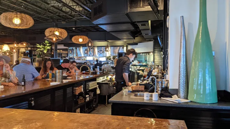 The copper-topped bar at Truffles Cafe in Sea Pines, with woven pendant lights and the open kitchen behind it