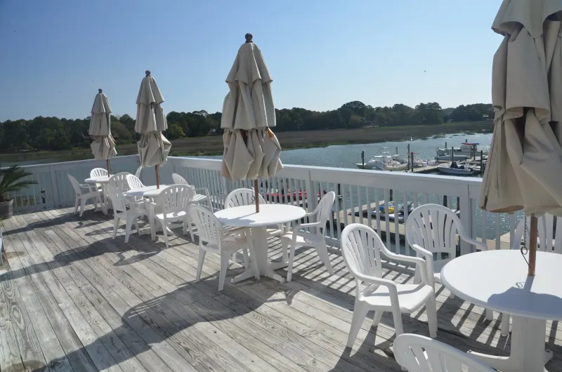 White tables and folded umbrellas on the Wreck of the Salty Dog’s deck over South Beach Marina