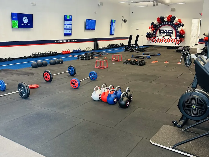 The F45 Training floor at The Plaza at Shelter Cove, with barbells, kettlebells, plyo boxes and workout screens on the walls