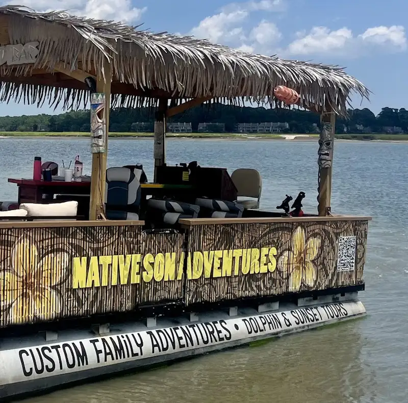 The Native Son Adventures tiki boat, a pontoon with a thatched roof, pulled up in the shallows of a wide tidal creek
