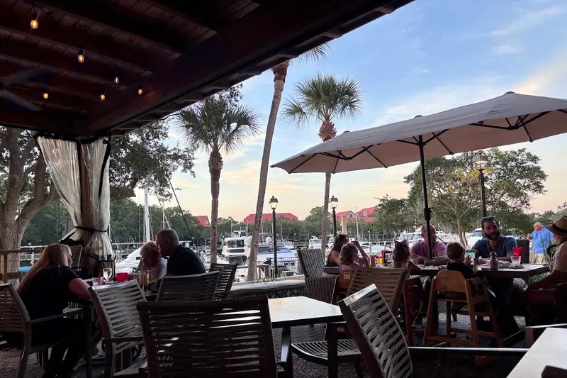 Top Dawg Tavern’s covered patio at Shelter Cove Harbour, with palms and the marina beyond the umbrellas