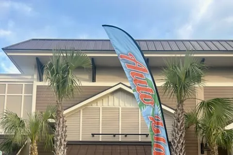 The front of the Auto Island clubhouse in Bluffton, with palm trees and a feather flag by the door