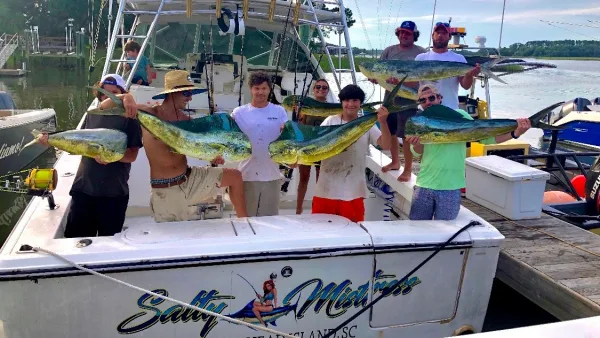 Anglers on the Above and Below Charters boat holding up mahi-mahi at the dock