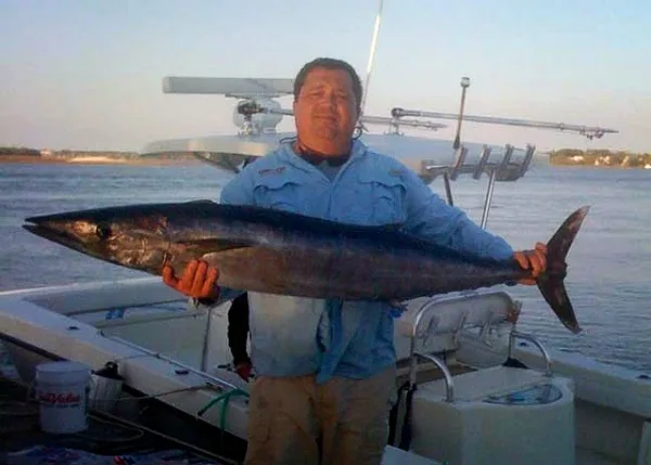 Captain holding a king mackerel aboard the Cool Cat Sportfishing boat