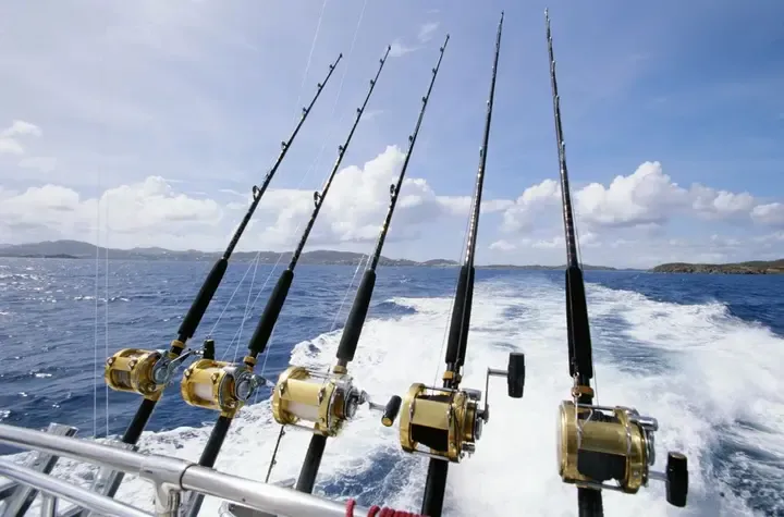 Trolling rods in the rod holders, with the wake behind a Gone Fishing HHI charter boat