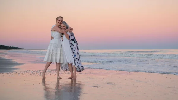 Two people posing at the water's edge at sunset for Island Life HH Photography