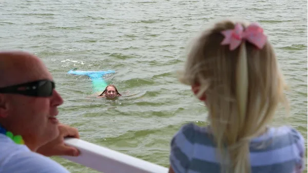 A child watching the mermaid swim beside the Mermaid of Hilton Head boat