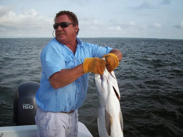 The Polecat Sport Fishing captain holding up a fish on the boat