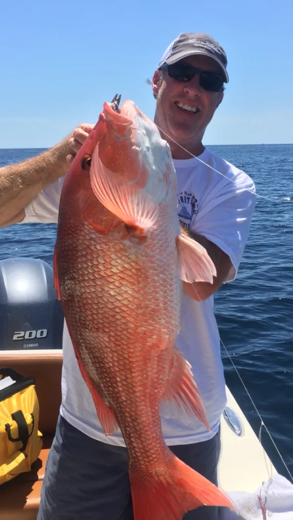An angler holding a red snapper on a Reel Easy Charters trip