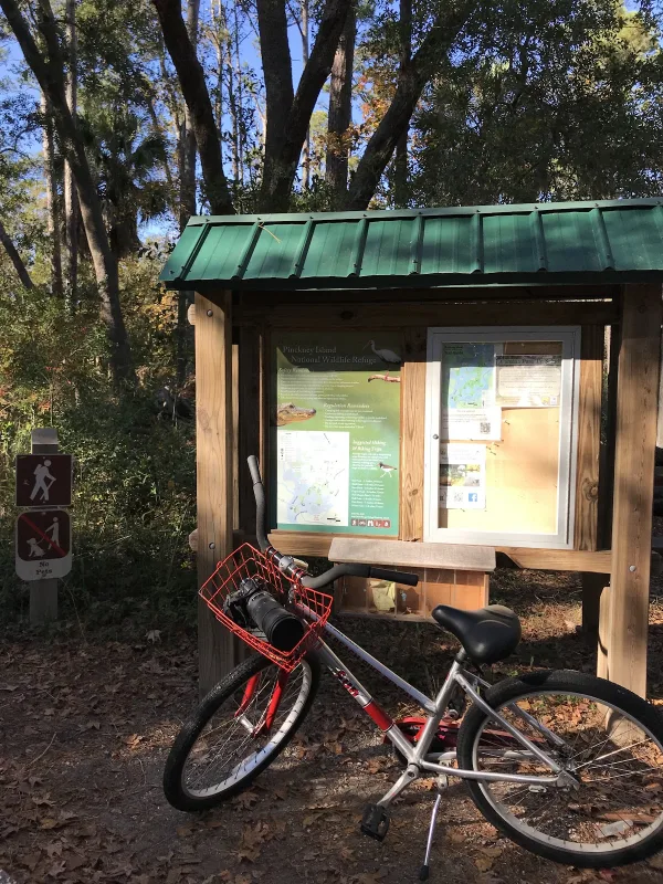 A South Beach Bike Rentals bike parked by a trail map board in Sea Pines