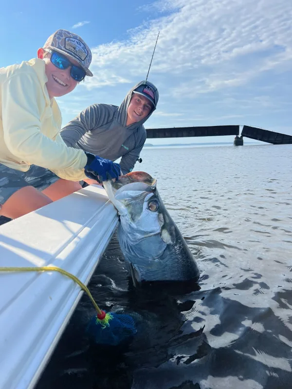 Captain and angler landing a fish over the side of the Still Playin boat