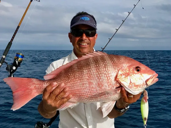 Captain John holding a red snapper aboard Sweet Pea Fishing