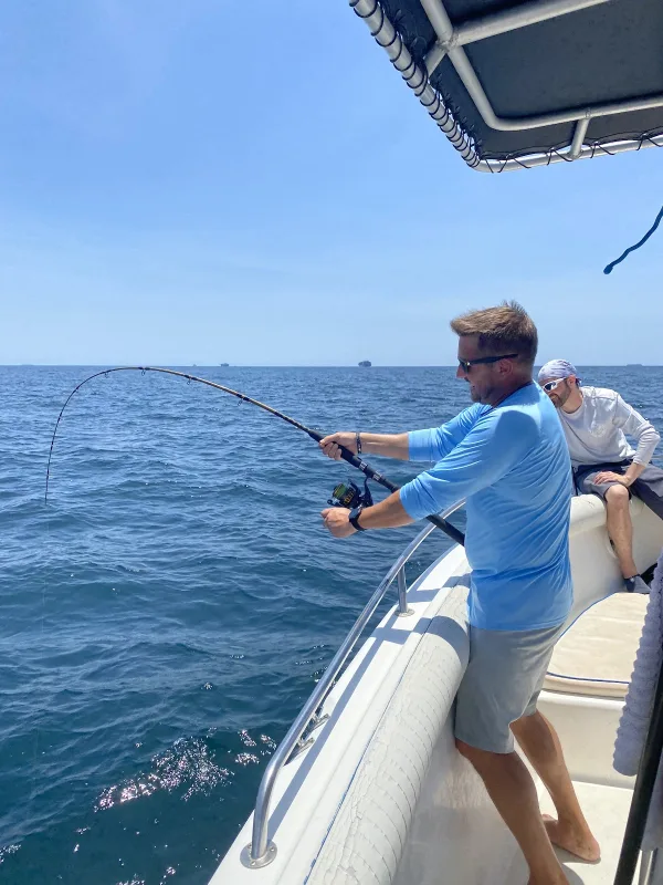 An angler fighting a fish from a Tail Tamer Fishing Charters boat