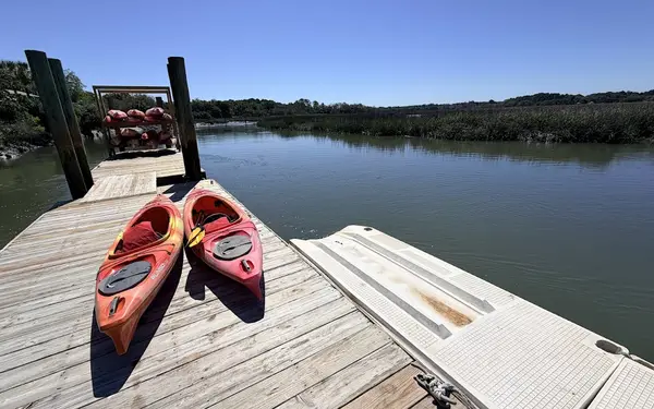 Two red kayaks on a floating dock over Jarvis Creek, with a rack of kayaks and the marsh behind