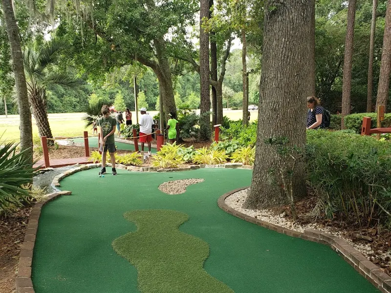 A putting green curving between pines and live oaks at Legendary Golf, with a flag marking the hole
