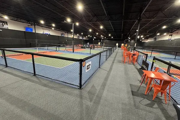 Indoor pickleball courts at Dill Dinkers, with orange tables and chairs along the side