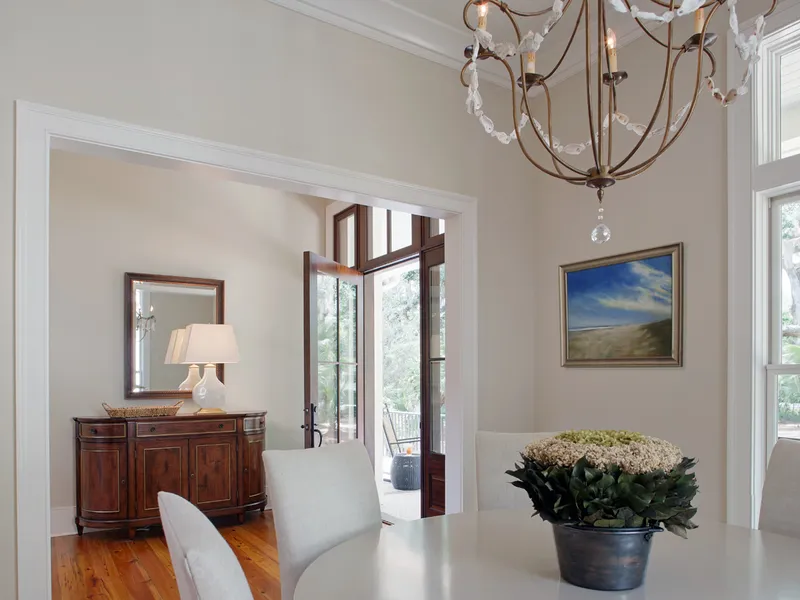 A dining room styled by J. Banks Design, with a shell-draped chandelier and a beach painting