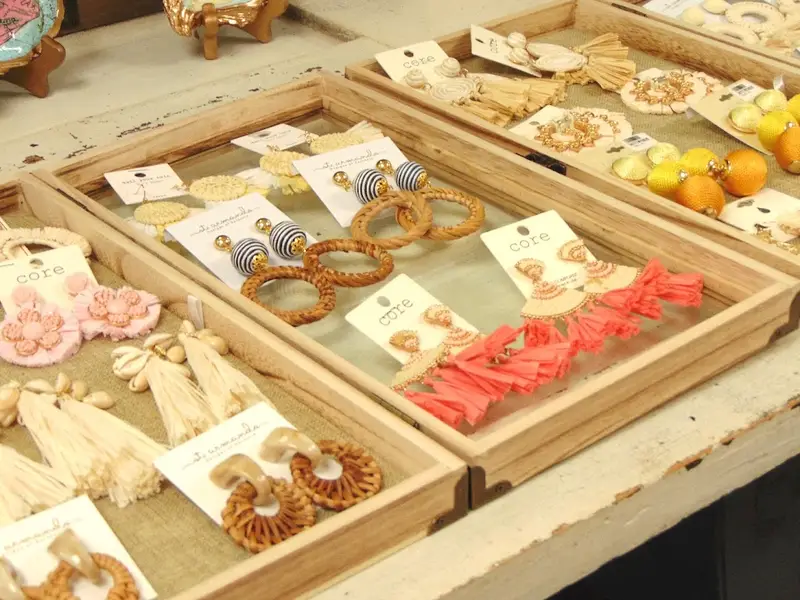 Raffia tassel and beaded earrings laid out in wooden trays at Lowcountry Mercantile