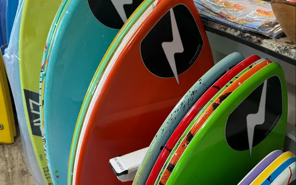 Brightly coloured skimboards and bodyboards standing in a rack in the Soul SUP shop