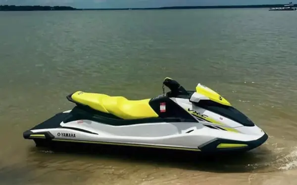 A white and yellow jet ski pulled up in the shallows at the water’s edge