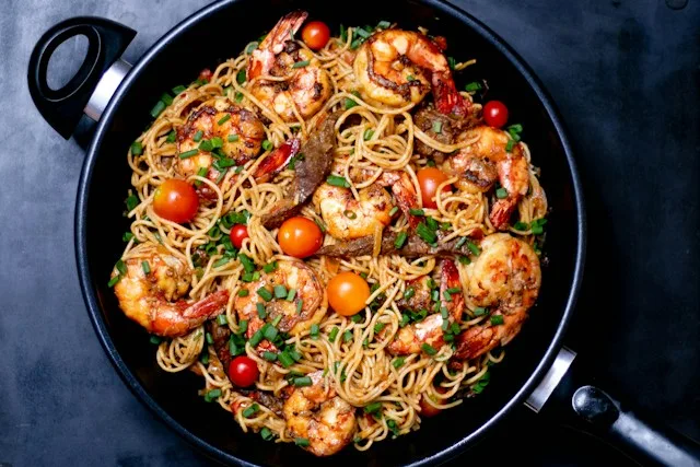 Skillet of shrimp pasta with cherry tomatoes and chives